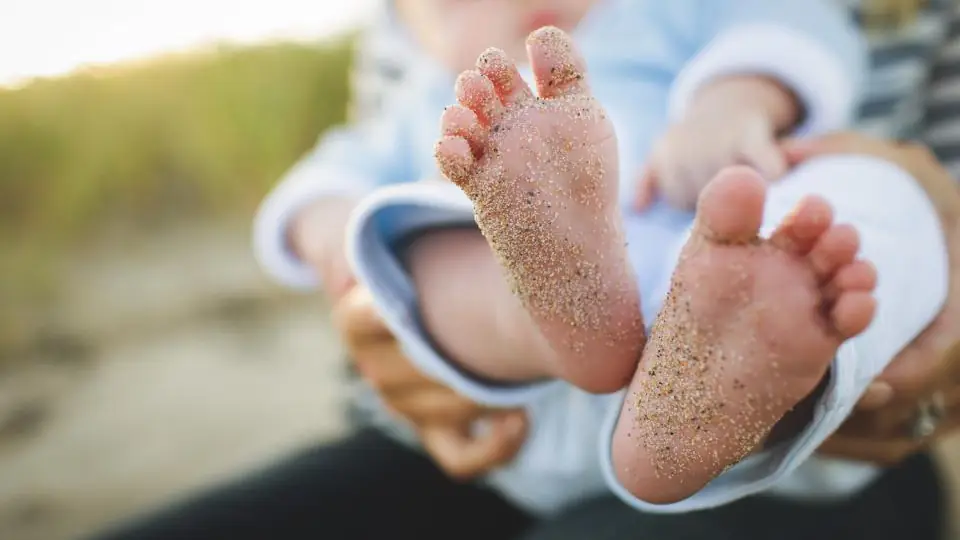A baby's feet held by a parent